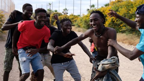 Varios migrantes se dirigen al Centro Temporal de Inmigrantes (CETI) mientras celebran el salto de la valla de Melilla