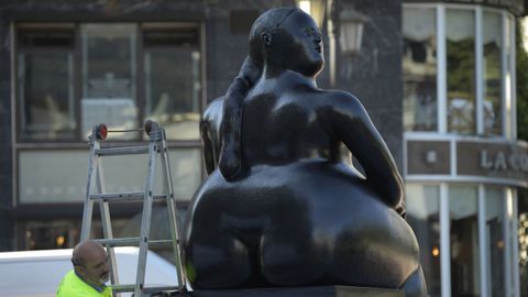 Un operario pinta la escultura urbana La Maternidad , del artista Fernando Botero, en la plaza de Escandalera, en Oviedo