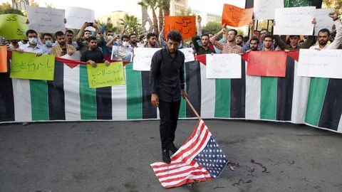 Un manifestante a punto de quemar una bandera estadounidense durante una manifestación en Teherán (Irán)
