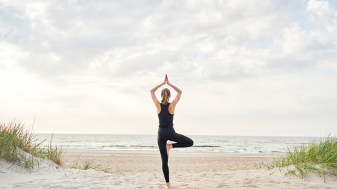Hacer yoga o estiramientos en la playa es una opción recomendada por los expertos para manternos activos en vacaciones. 