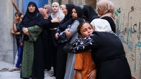 Una mujer consuela a una niña durante el funeral de cuatro adolescentes en Gaza