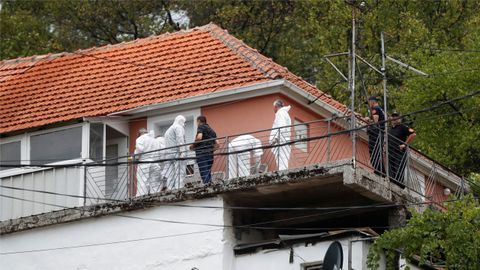 Varios policías científicos recogen evidencias en la casa familiar donde se produjo en tiroteo, en Medovina