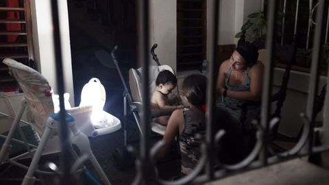 Una mujer conversa con sus hijos con la luz de una lámpara durante un apagón.