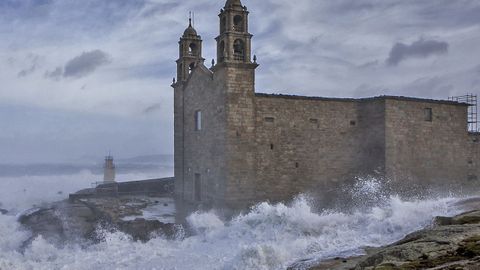 El mar llega hasta el santuario de la Virxe da Barca de Muxía durante un temporal.
