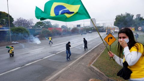 Seguidores del derrotado Bolsonaro huyen de los botes de humo en una protesta en la ciudad brasileña de Barueri.