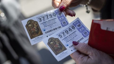 Una mujer sostiene dos dcimos de la lotera del Nio