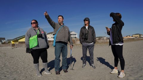 Varios vecinos observan en una playa de Carolina del Norte la trayectoria del globo antes de ser derribado por un caza.