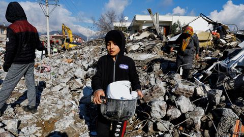 Un nio recoge utensilios de su vivienda derribada por el terremoto en Gaziantep