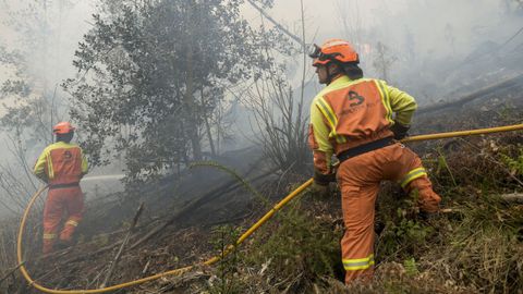 Unos bomberos trabajan en las labores de extincin del incendio declarado en Navelgas, en Asturias