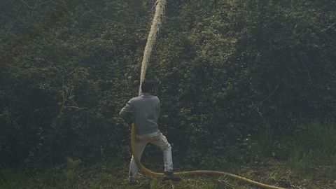 Un vecino trabaja en las labores de extincin del incendio forestal en Luarca
