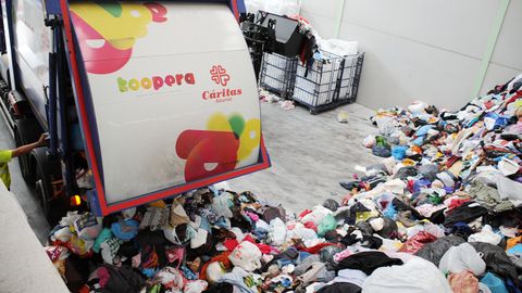 Un camión de reciclaje de Koopera (Cáritas) deposita en su nave de Asturias la ropa recogida para clasificar, reutilizar o reciclar