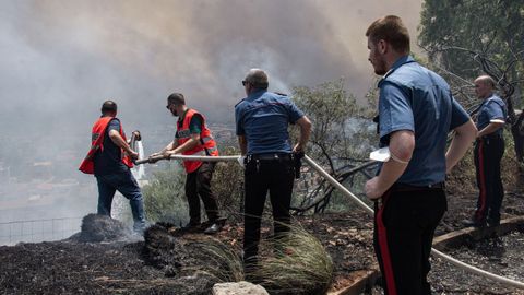 Agentes de polica ayudan a los lugareos a apagar un incendio forestal que se aproxima a las casas en Palermo, Sicilia.