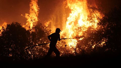 Un bombero trata de apagar el fuego que arde cerca de la zona industrial de Volos, en Grecia