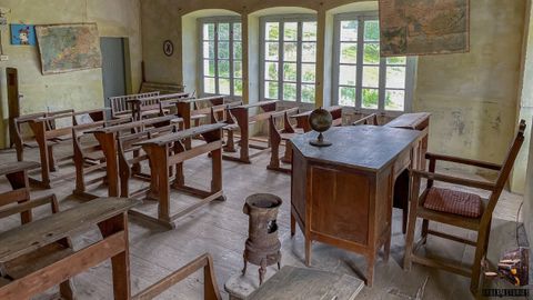 Un aula de una escuela de la Asturias rural cerrada con los pupitres intactos.