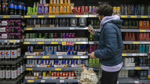 Un joven observa bebidas energéticas de distintas marcas en un supermercado