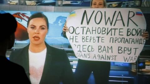 La periodista rusa Marina Ovsyannikova, al fondo, con el cartel contra la guerra que exhibió en medio de un informativo.