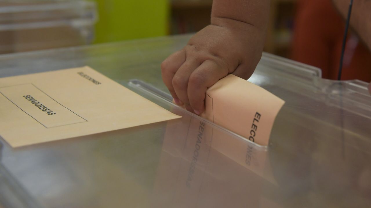 Una nia ayuda a sus mayores a votar en las elecciones generales en un colegio de Avils