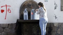 Una vecina recoga agua este lunes en la fuente de Fenosa, en la Travesa de Vigo