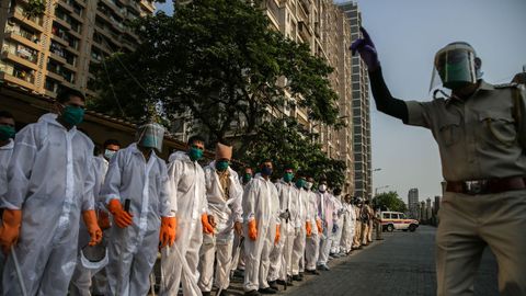 Un oficial explica a agentes de la polica india cmo emplear los trajes de proteccin, en las calles de Mumbai