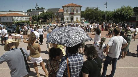 Tres personas se protegen del sol bajo el mismo paraguas durante el concierto de la Banda de Sober