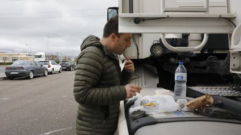 Un camionero aprovecha un espacio externo del vehculo para comer en el polgono de San Cibrao, en Ourense