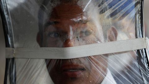 Zaul Ortega, de 53 años, se cubre el rostro con una bolsa plástico mientras hace fila para comprar en un supermercado en Ciudad de Panamá