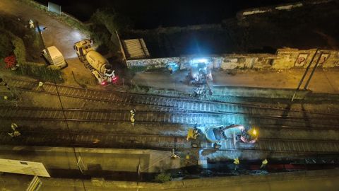 Los obreros derribando un muro de madrugada junto a la va del tren de Lugo