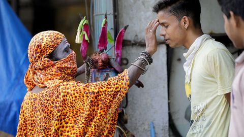 En Calcuta, un monje con máscara facial bendice a un joven