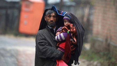 Un cachemir protege a su beb con una chaqueta durante un da lluvioso en Srinagar, capital estival de la Cachemira india.