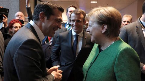 El primer ministro griego Alexis Tsipras, el presidente francs Emmanuel Macron y la canciller alemana Angela Merkel sonren mientras hablan en un pasillo al final del Consejo Europeo