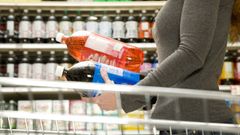 Una mujer sostiene dos botellas de refrescos azucarados en un supermercado