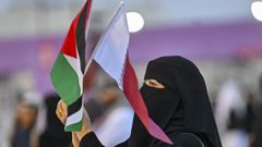 Una catarí con la bandera palestina y de su país. 