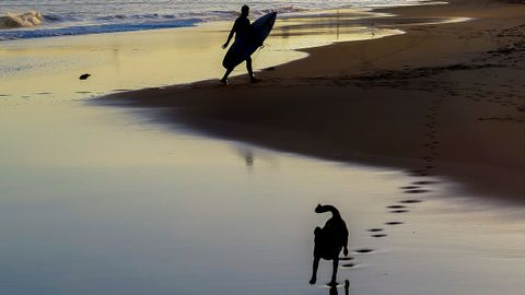 Un hombre con su tabla de surf a primera hora de la maana por la playa donostiarra de Ondarreta. 