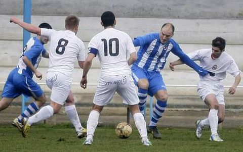 David, jugador del Iberia, rodeado por futbolistas de la Sarriana en un partido en As Valgas.
