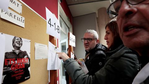 Varias personas consultan el censo electoral en un colegio.