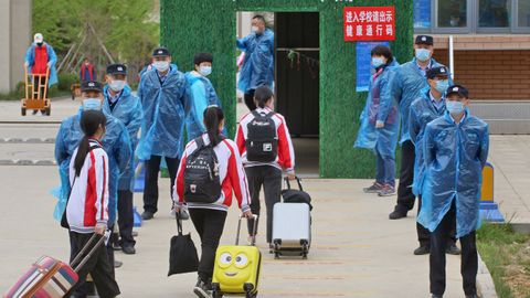 En la localidad china de Yantai los estudiantes han regresado a las aulas. Los policías supervisan su entrada con mascarillas y batas plásticas