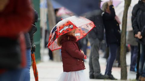 Una nia disfrazada y con paraguas entre el pblico que segua el desfile en el barrio de la Estacin