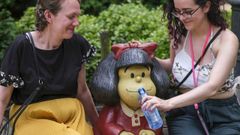  Dos turistas simulan dar agua a la escultura que representa a Mafalda, el personaje crado por el humorista grfico argentino  Quino , en el Campo de San Francisco en Oviedo