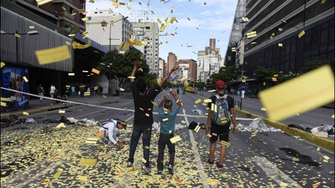 Tres jvenes lanzan al aire billetes de metro sin usar durante una protesta en Caracas