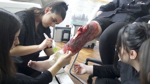 En la imagen, alumnas de estética creando una herida falsa con apariencia muy real