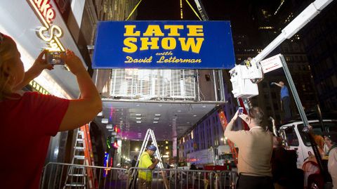 La gente tomas fotos de los trabajadores quitan el anuncio qu epromocionaba el show de David Letterman. 