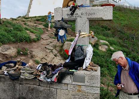Una placa y otros objetos recuerdan a los fallecidos en la cruz de la punta del Cabo de Fisterra.