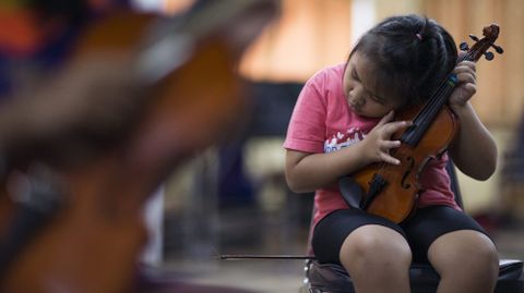 La estudiante invidente Cholticha Iamvijit, de 10 aos, componente de la Orquesta de Invidentes de Tailandia, afina el violn durante un ensayo la banda en la Escuela para Invidentes e Invidentes con Multiminusvalas en la provincia de Lopburi (Tailandia) el 12 de mayo de 2016.