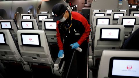 Un trabajador de Japan Airlines desinfecta la cabina del avión tras un vuelo doméstico