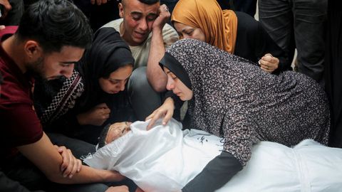 Varios gazates lloran alrededor de un cuerpo, durante un funeral en Rafah.