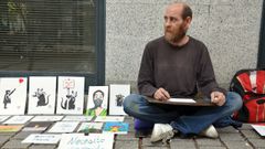Israel, sentado en la Praza da Independencia de Vigo, dibujando sus imitaciones de Banksy