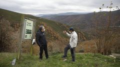 Dos vecinos observan el paisaje junto a un cartel de la localidad, en una imagen de archivo.