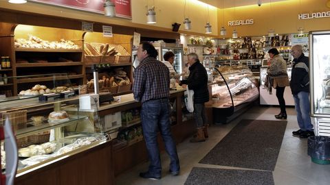 Cuatro personas, separadas entre ellas, haciendo compras en una pastelera