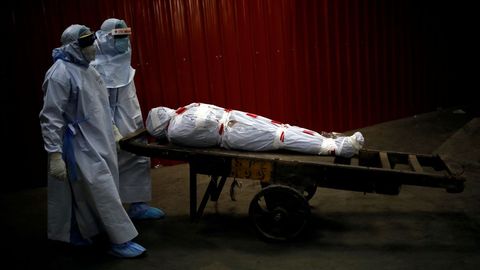 Sanitarios portan en Nueva Dehli el cuerpo de un fallecido por covid-19