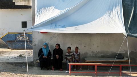 Cuatro migrantes se sientan en un campo de refugiados en Lagadikia